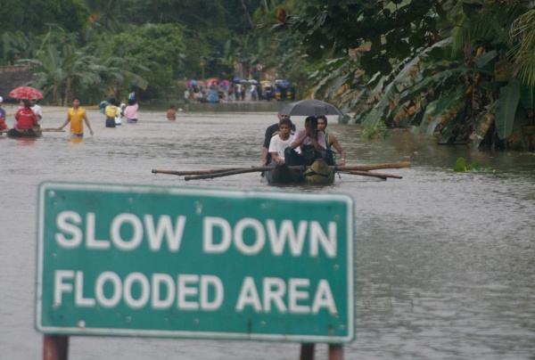 Residents paddle across a flooded portion of the national highway in Santiago, Agusan del Norte Wednesday. Hundreds of commuters have been stranded when the national highway was closed due to flood since Tuesday evening. Mindanews Photo by Ruby Thursday More