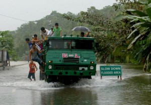 A truck transports residents across a flooded portion of the national highway in Santiago, Agusan del Norte on Wednesday. Hundreds of commuters have been stranded when the national highway was closed due to flood since Tuesday evening. Mindanews Photo by Keith Bacongco