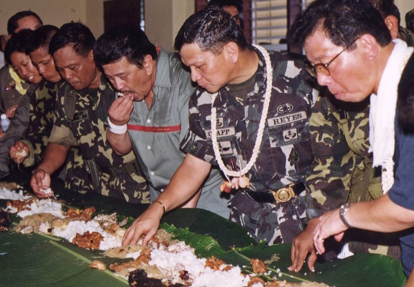 The late Angelo T. Reyes (2nd from right), then chief of staff of the Armed Forces, joins former President Joseph Estrada and Defense Secretary Orlando Mercado in a boodle fight in Kauswagan, Lanao del Norte during the “all out war” in 2000. MindaNews file photo by Bobby Timonera
