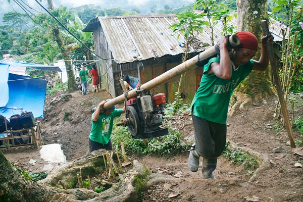 HEAVY BURDEN. Laborers carry a heavy machine for ball mills up into the mountains in Sitio Panganason-B, Barangay Kingking, Pantukan, Compostela Valley Province. Local authorities have declared the village as a danger zone in the wake of the deadly landslide that killed at least 13 miners almost a week ago and ordered all residents to vacate the area. MindaNews Photo by Ruby Thursday More