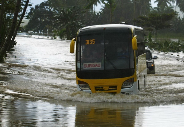 A bus navigates through the flooded portion of the national highway in Kitcharao, Agusan del Norte on Thursday. Mindanews Photo by Keith Bacongco