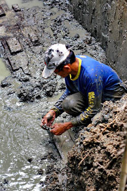 A technician from the National Museum carefully cleans the wooden hull of the fourth balanghai boat being excavated in Barangay Libertad, Butuan City on May 29, 3012. Nine of such ancient boats were discovered in the 1970s, but only three were excavated then. MindaNews photo by Erwin Mascarinas