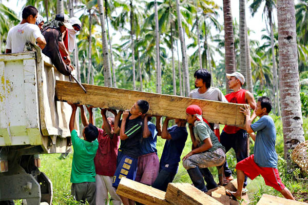 BAYANIHAN. Laborers haul a big Lauan lumber into a waiting truck in Barangay Pianing in Butuan City on June 18, 2012. Authorities seized 429 pieces of lumber in barangay Pianing last Saturday, June 17, 2012. MindaNews photo by Erwin Mascarinas