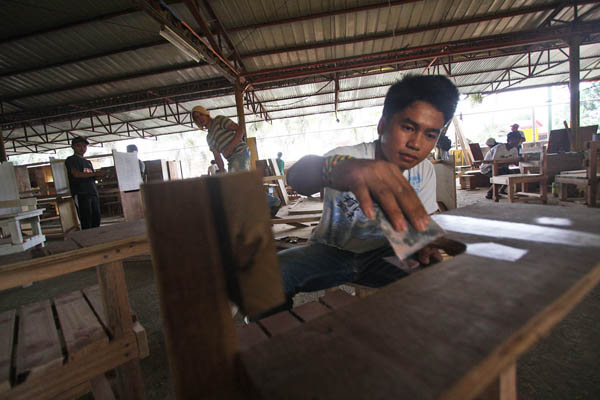 FINISHING TOUCHES. A worker puts finishing touches on a school chair at the Tagum City Motorpool. The city government has made school chairs from seized illegal lumber instead of leaving them to rot. MindaNews photo by Ruby Thursday More