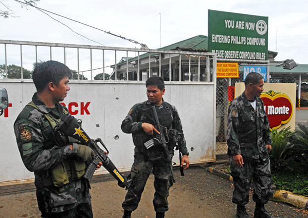 A group of policemen watch the gate of the Del Monte compound in Camp Phillips, Manolo Fortich in Bukidnon on Feb. 20, 2013 after NPA rebels attacked the facility killing a security guard and wounding three other persons. MindaNews photo by Froilan Gallardo