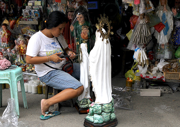 A vendor installs the "halo crown" of the statue of Virgin Mary at her stall outside the San Pedro Cathedral in Davao City. Mindanews Photo by Keith Bacongco