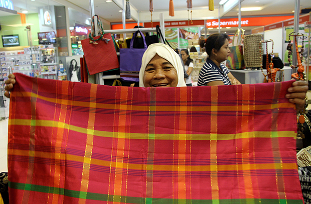 Bai Nola Mama, 63, shows an inaul, a hand-woven cloth from Maguindanao, at the Mindanao Trade Expo 2013 in Abreeza Mall, Davao City. The MTE, which showcases different Mindanao-made products, is one of the major events of the Kadayawan Festival that will end on Friday, August 16. MindaNews photo by Keith Bacongco