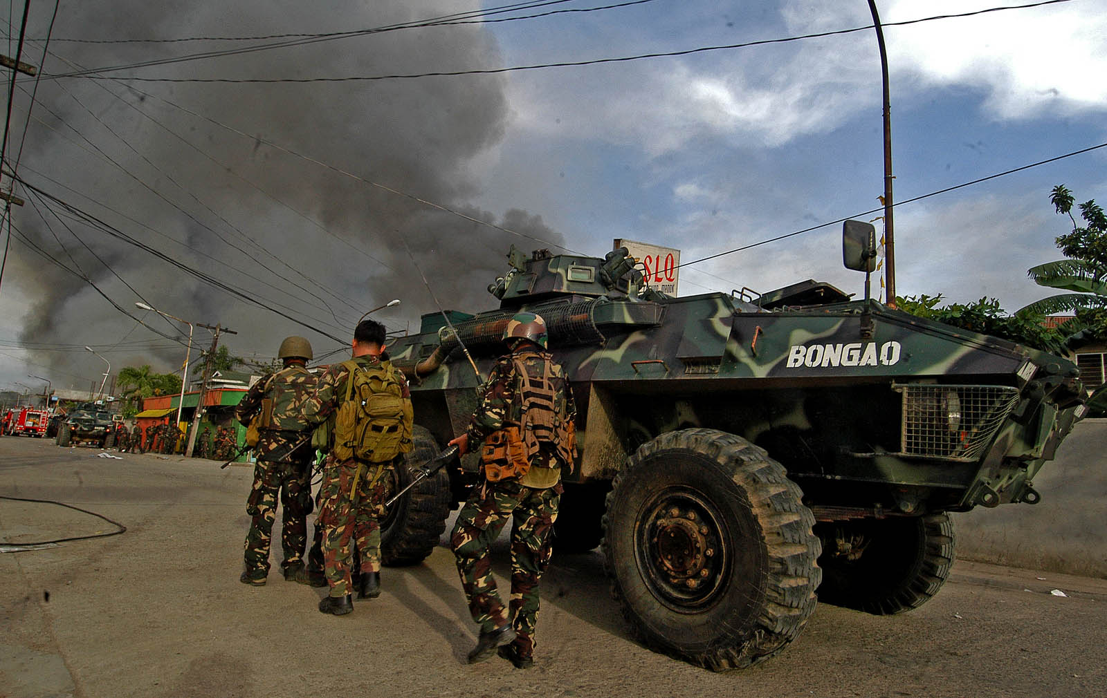 ARMOR COVER. Soldiers used the cover behind a Simba tank as they cross a street filled with rebel snipers in Evangelista Street, Barangay Santa Catalina in Zamboanga City on Thursday, Sept. 12. MindaNews photo by Froilan Gallardo
