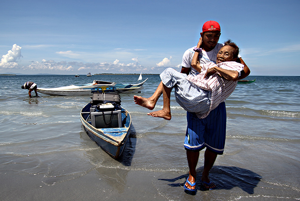 CARRIED TO SAFETY. A 90-year old Tausug woman from Barangay Mariki is carried to the shoreline after a forced evacuation was ordered  by the city government in the six conflict-affected barangays and neighboring villges in Zamboanga City on Friday, September 13. The city has 98 barangays. MindaNews photo by Erwin Mascarinas 