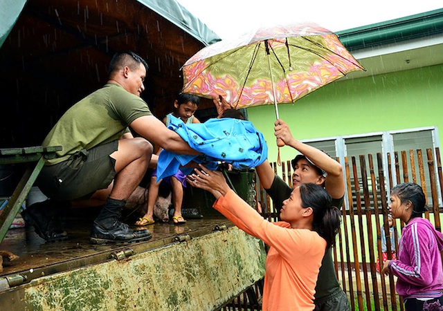 EVACUATION.  A couple hands over their baby to a soldier before boarding an Army truck  in Barangay Cala-anan, Cagayan de Oro City on Jan. 20. Rains brought by  tropical depression “Agaton”  triggered floods in the city and Misamis Oriental province. Photo courtesy ofr Cagayan de Oro Information Office/ Rhoel Condeza