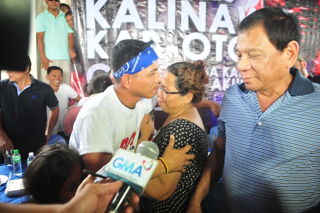 Freed1 FREED. Davao City mayor and Presidential candidate Rodrigo Duterte, answers questions from reporters as Army Sgt. Adriano Bingil hugs his mother, Myrna, after the New Peoples Army released him Thursday after 104 days in captivity. Bingil was released to Duterte and the Philippine Ecumenical Peace Platform in Barangay Durian, Las Nieves, Augsan del Norte on New Year’s eve, December 31, 2015. MindaNews photo by Froilan Gallardo 