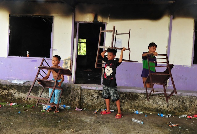BURNED. Students carry their chairs from the burnt building of the Dilausan Primary School in Barangay Dilausan, Tamparan town on Monday, May 9, 2016. Unidentified men set on fire the building hours before the opening of the polls at 6 a.m. The voting continued with Comelec officials transfering the voters to another venue. MindaNews photo by FROILAN GALLARDO 