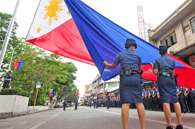 118TH PHILIPPINE INDEPENDENCEDAYFemale police officers carry a big Philippine flag during the 118th Independence Day rites in Divisoria, Cagayan de Oro on June 12, 2016. MindaNews photo by Froilan Gallardo