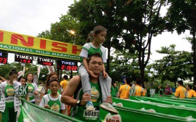 A father carries his daughter as he crosses the finish line during the 40th National Milo Marathon early Sunday. MindaNews photo by Antonio L. Colina IV 