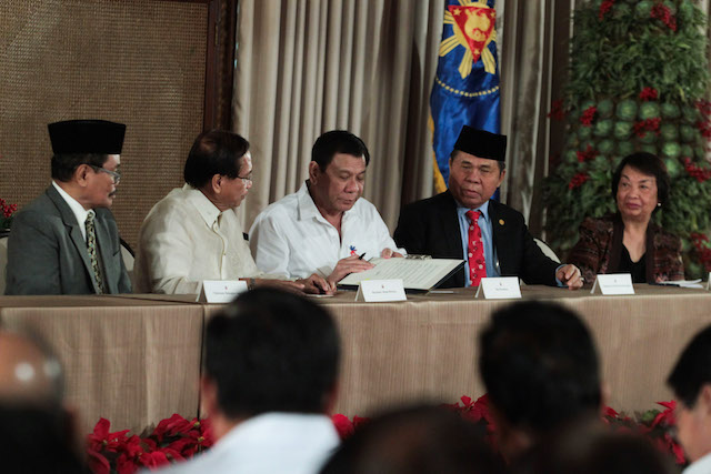 President Rodrigo Roa Duterte signs the Executive Order reconstituting the Bangsamoro Transition Commission in Malacañan on November 7. Also in the photo are Moro Islamic Liberation Front (MILF) Peace Implementing Panel chair Mohagher Iqbal, Presidential Peace Adviser Jesus Dureza, MILF Chair Al Haj Murad Ebrahim, and Government of the Philippines (GPH) Peace Implementing Panel chair Irene Santiago. KING RODRIGUEZ/Presidential Photo 